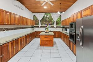 Il comprend une grande cuisine avec des placards en bois et un réfrigérateur. dans l'établissement Amazing VillaF 5 min from Coco Beach, à Coco