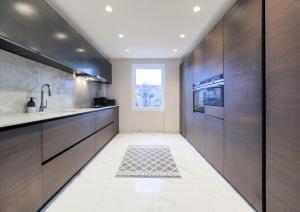 a kitchen with wooden cabinets and a sink at Luxury 3 Bedroom Flat in Maida Vale in London