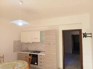 uma cozinha com armários brancos e uma mesa num quarto em Casa Azzurra 56 em Bova Marina