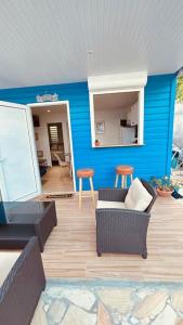 a living room with a blue wall with a couch and stool at Studio Bis Océan 2 personnes Sainte-Anne plage in Sainte-Anne