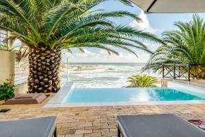 a swimming pool with a palm tree and the ocean at Camps Bay Terrace Palm Suite in Cape Town