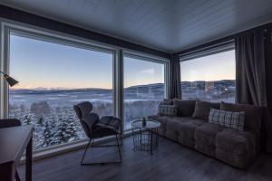 a living room with a couch and large windows at Aurora Borealis Observatory in Silsand