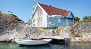 een klein huis met twee boten in het water bij Austefjorden Fjordsuite med Panoramautsikt in Forland