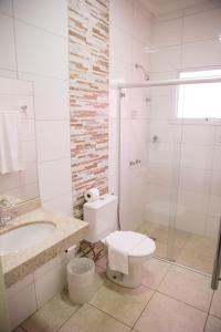 a bathroom with a toilet and a sink and a shower at Revitalle Hotel in Votuporanga