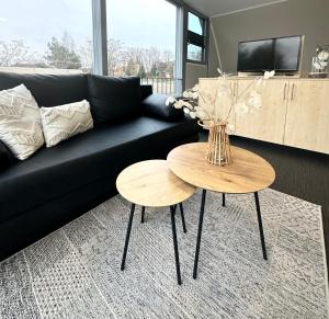 ein schwarzes Sofa mit zwei Tischen im Wohnzimmer in der Unterkunft Open-Water-Resort in Geierswalde