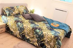 Ce lit se trouve dans un dortoir doté d'un couvre-lit avec des feuilles. dans l'établissement Zénith - Cartoucherie - Purpan, à Toulouse
