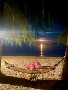 a person laying in a hammock on a beach at Marjoly Beach Resort in Telukbakau