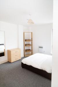 a white bedroom with a bed and a dresser at Serviced Apartment in Liverpool City Centre - Free Parking - Balcony - by Happy Days in Liverpool