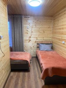 two beds in a room with wooden walls at Syi-Ordo Hotel in Pokrovka