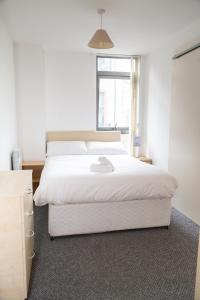 um quarto com uma grande cama branca e uma janela em Serviced Apartment in Liverpool City Centre - Free Parking - Balcony - by Happy Days em Liverpool
