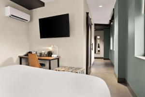 a hotel room with a bed and a desk with a tv at CityFlatsHotel - Port Huron, Ascend Hotel Collection in Port Huron