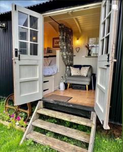 una puerta abierta de una casa pequeña con una silla en shepherd hut glamping in Northumberland en Newcastle