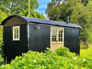 un cobertizo negro con una puerta y una ventana en shepherd hut glamping in Northumberland en Newcastle