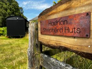 un cartel en una valla de madera que lee cabañas hereditarias de pastores en shepherd hut glamping in Northumberland en Newcastle