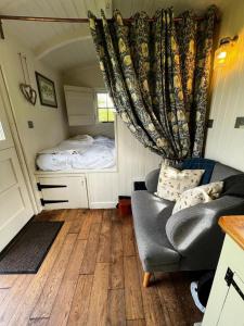 una habitación con sofá y cama en una casa pequeña en shepherd hut glamping in Northumberland en Newcastle