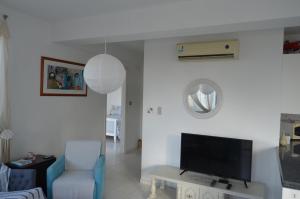 a living room with a tv and a blue chair at Mia's Cove in Paphos