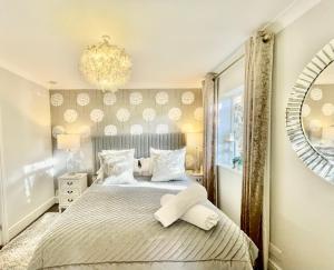 a bedroom with a bed with a mirror and a chandelier at Cotswold Chic Retreats "Jacinabox" 5 Star Chipping Campden-Parking-Garden in Chipping Campden