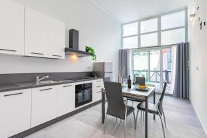 une cuisine avec des placards blancs et une table avec des chaises dans l'établissement Exclusive Loft - Life is Beautiful - Free WiFi - 5 min To Metro Nizza, à Turin