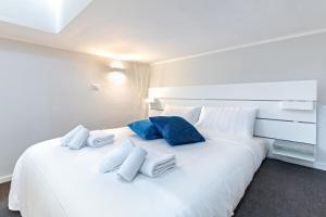 Una gran cama blanca con almohadas azules. en Exclusive Loft - Life is Beautiful - Free WiFi - 5 min To Metro Nizza, en Turín