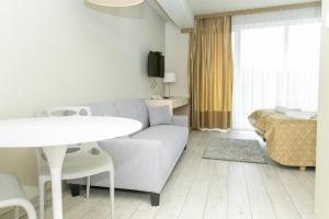 ein Wohnzimmer mit einem Sofa, einem Tisch und einem Bett in der Unterkunft VacationClub - Solden Apartament 33 in Heudorf
