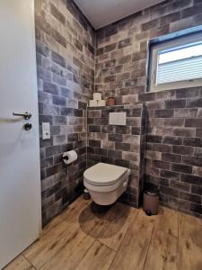 a bathroom with a toilet and a brick wall at Ferienwohnung Seeloft in Emden