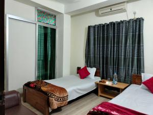 a hotel room with two beds and a window at New Hotel Shapno Nibash in Dhaka