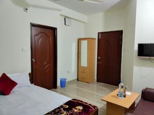 a bedroom with a bed and two doors and a table at New Hotel Shapno Nibash in Dhaka