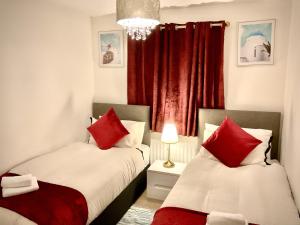 two beds in a small room with red curtains at Ocean-homestay in Colchester