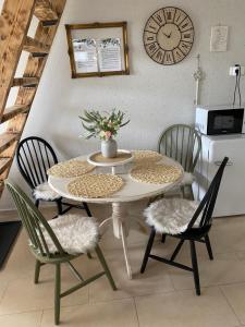 a dining room table with chairs and a clock on the wall at Somlói Provence in Doba