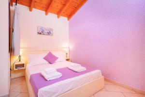 a bedroom with purple walls and a bed with towels at Thassos Neorion in Limenaria
