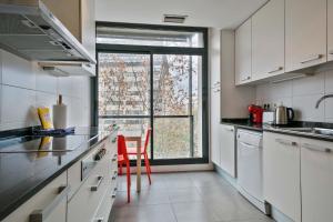 バルセロナにある1213 - Ciutadella Nice Apartmentの白いキャビネットと窓の前に赤い椅子が備わるキッチン
