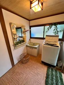 uma pequena cozinha com um lavatório e um fogão em 洋々庵・古民家一棟貸・完全貸切・プライベートサウナ em Furuyu
