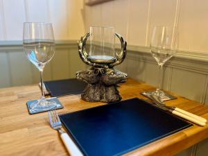 una mesa con dos copas de vino y un cabecilla de ciervo en The Deer Hut en Burpham