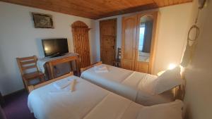 2 Betten in einem Zimmer mit einem TV und einem TV in der Unterkunft Casa Ciubărului Bran in Predeluţ