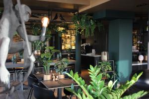 un restaurant avec des tables et des plantes en pot dans l'établissement Hotel Hogerhuys - adults only, à Noordwijk aan Zee