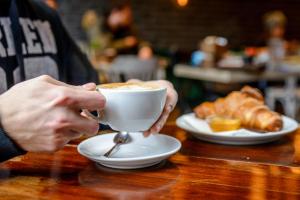 a person holding a cup of coffee on a table at Taksim Leon's Hotel in Istanbul