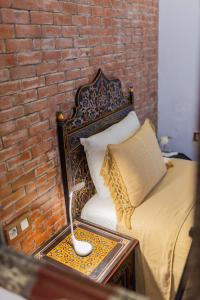 1 dormitorio con cama y pared de ladrillo en Casa Sabila, en Chefchaouen