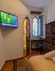 uma sala com uma televisão na parede e um quarto em Casa Sabila em Chefchaouen
