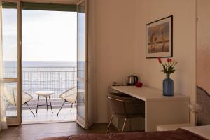 een slaapkamer met een bureau en uitzicht op de oceaan bij Cas’ A Mare - Beachfront Luxury Suites in Salerno