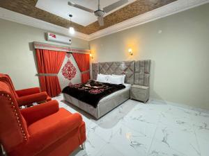 um quarto com uma cama e uma cadeira vermelha em Decent Lodge Guest House F-10 em Islamabad