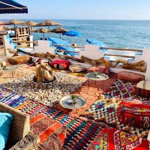 a beach with a bunch of blankets and pillows and the ocean at Room in Agadir Morocco in Agadir