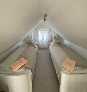 two beds in a attic room with a window at Somlói Provence in Doba