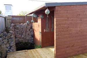 a wooden shed with a stone wall and a door at Holiday House with garden and sauna in Durness