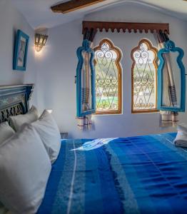 a bedroom with a blue bed with two windows at Casa Sabila in Chefchaouen +61 photos