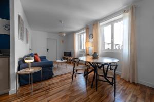 a living room with a table and a blue couch at Résidence Léon Blum - Appartements design - Parking in Clermont-Ferrand