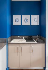 - une cuisine avec un évier et un mur bleu dans l'établissement Résidence Léon Blum - Appartements design - Parking, à Clermont-Ferrand