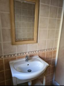 La salle de bains est pourvue d'un lavabo blanc et d'un miroir. dans l'établissement Le Hameau de cure, à Cazouls-lès-Béziers