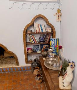 a room with a table and a shelf with books at Casa Sabila in Chefchaouen