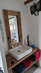 La salle de bains est pourvue d'un lavabo blanc et d'un miroir. dans l'établissement Gite La Passerelle, à Ostheim