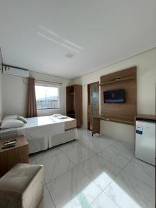 ein großes Schlafzimmer mit einem großen Bett und einem TV in der Unterkunft Hotel Carvalho in Ibiapina